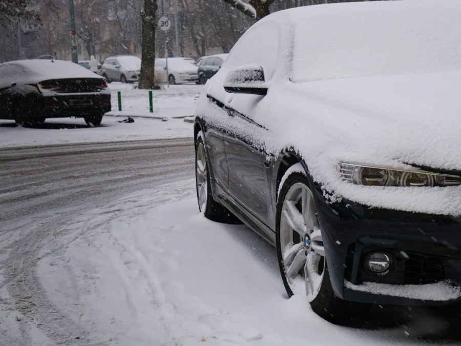 Car covered in fresh snow parked on a snowy street
